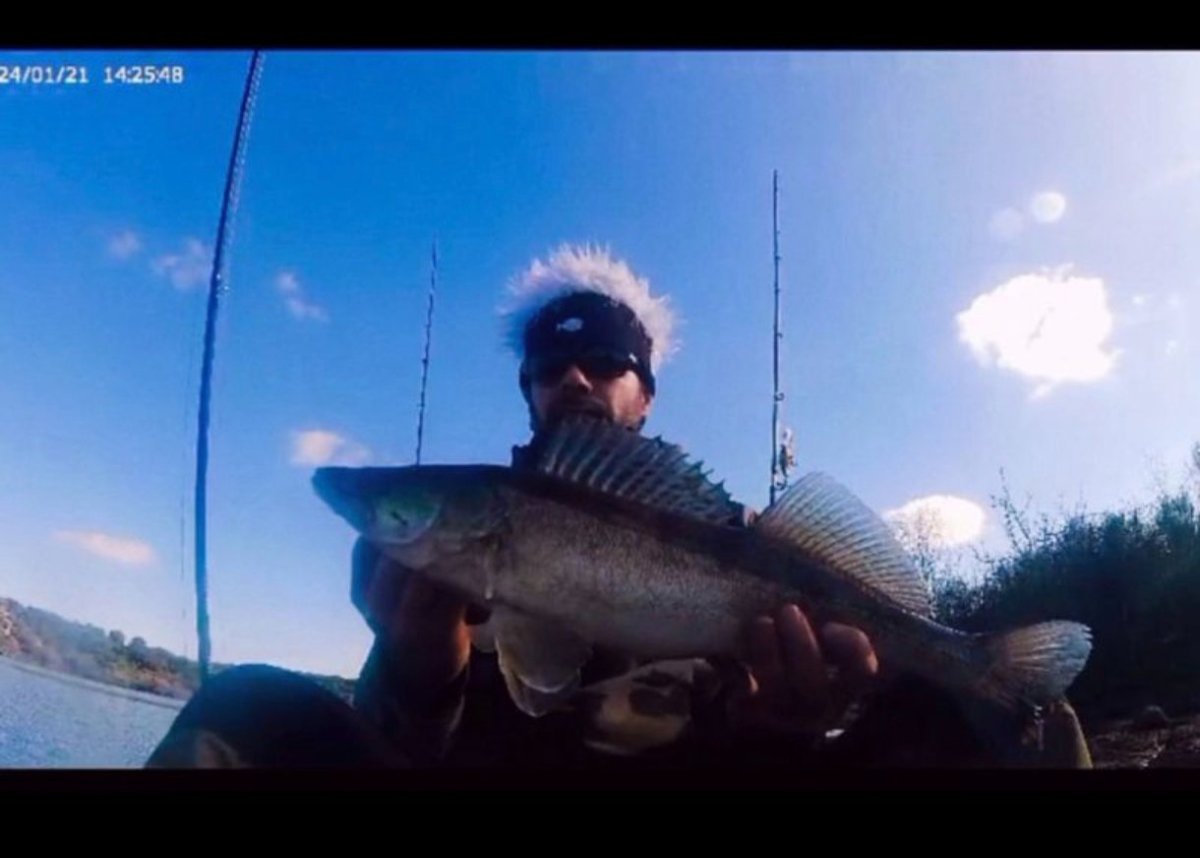 Pescador lanzando un jig metálico desde una punta de roca al amanecer, iniciación al jig-casting